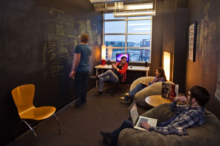 three people sitting on bean bag chairs in a room with chalk writing on the wall