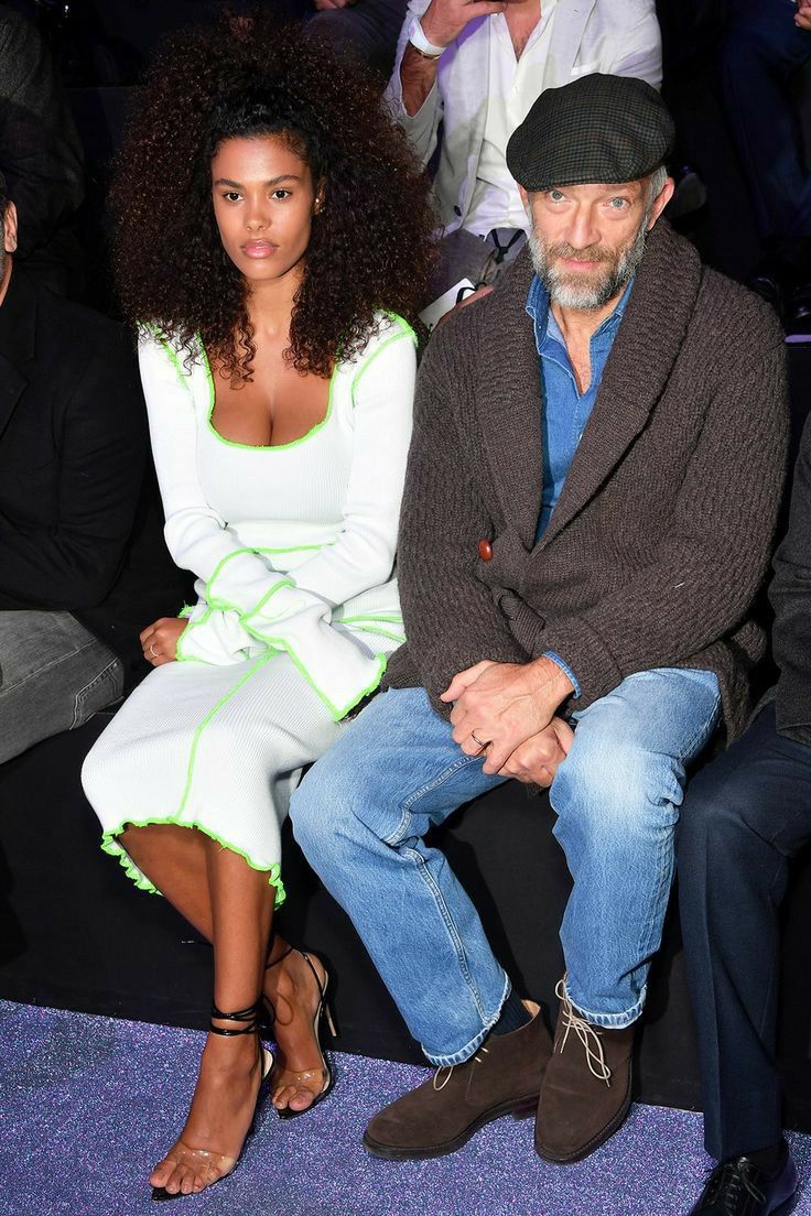 an older man and woman sitting next to each other at a fashion show