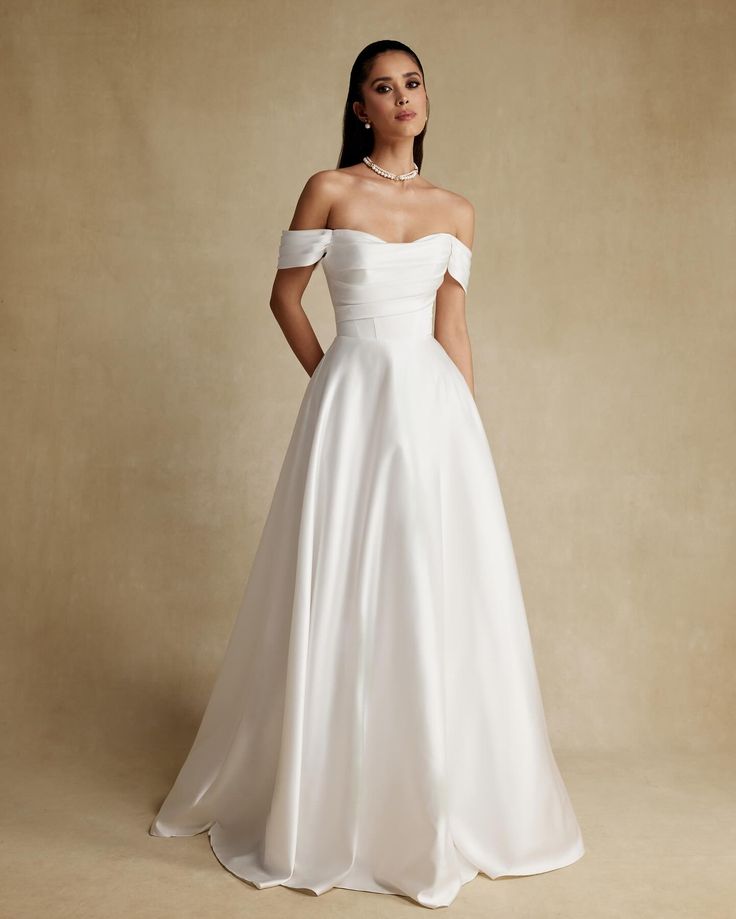 a woman in a white wedding dress posing for the camera with her hands on her hips