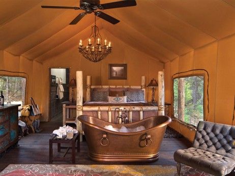 an old fashioned bathtub in the middle of a room with large windows and chandelier