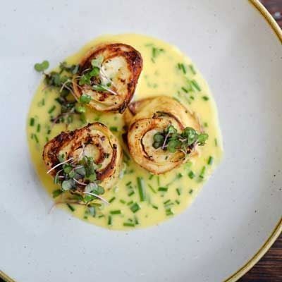 three scallops on a white plate with green garnish