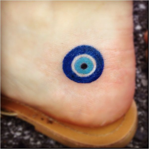 an eyeball tattoo on the foot of a person's foot, with blue ink