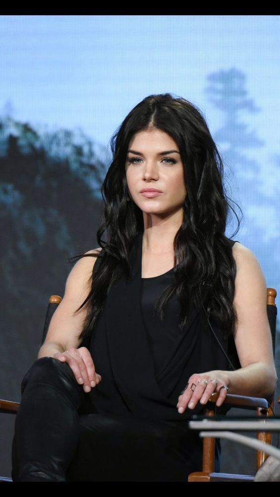 a woman with long black hair sitting in a chair