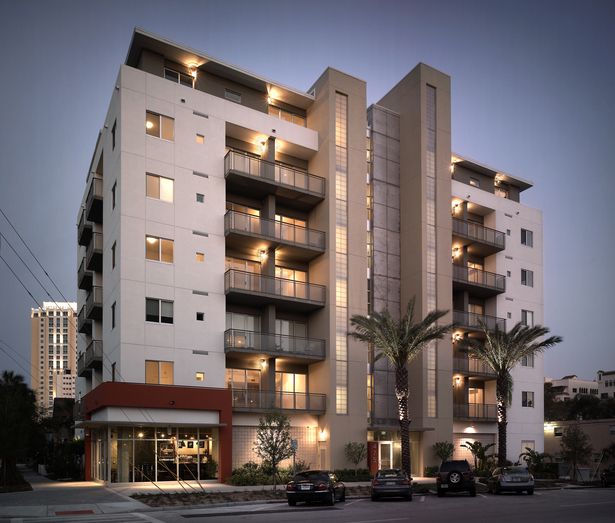 an apartment building with cars parked on the street in front of it at night time