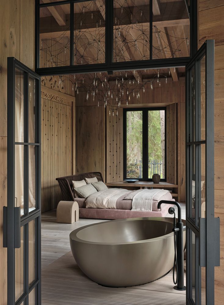 a large bathtub sitting in the middle of a room next to a bed and window