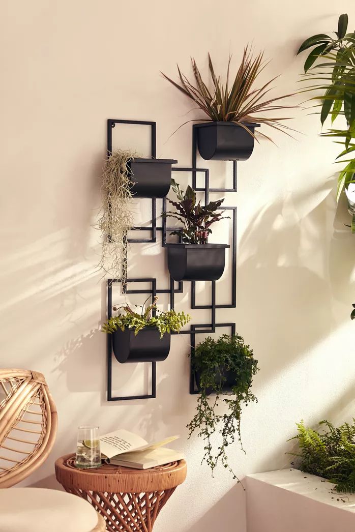 a wall mounted planter filled with plants next to a wicker chair and table