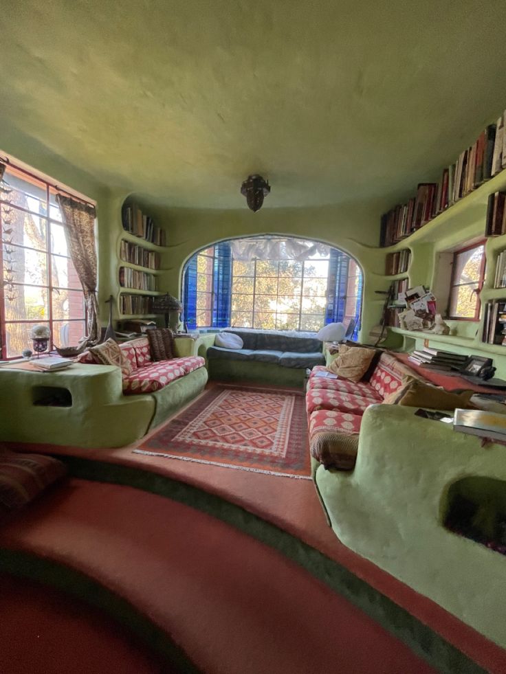 a living room filled with furniture and bookshelves next to a large open window