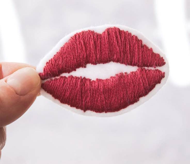 a person holding a piece of felt with a red lip painted on it