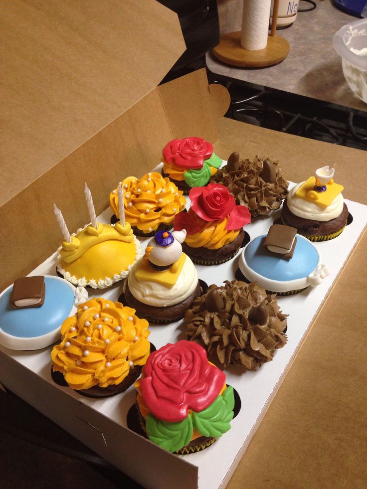 a box filled with lots of cupcakes covered in frosting and decorations on top of each other