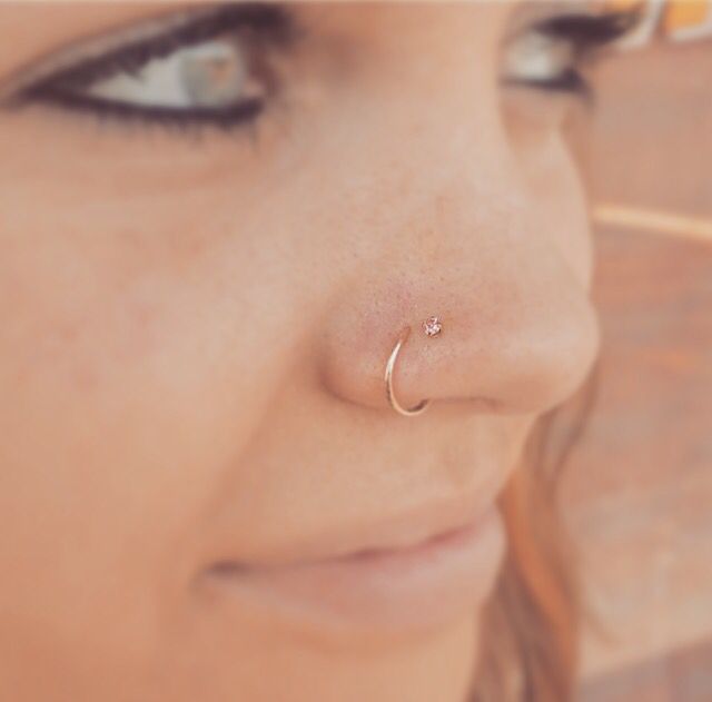 a close up of a woman with a nose piercing on her nose and an ear ring