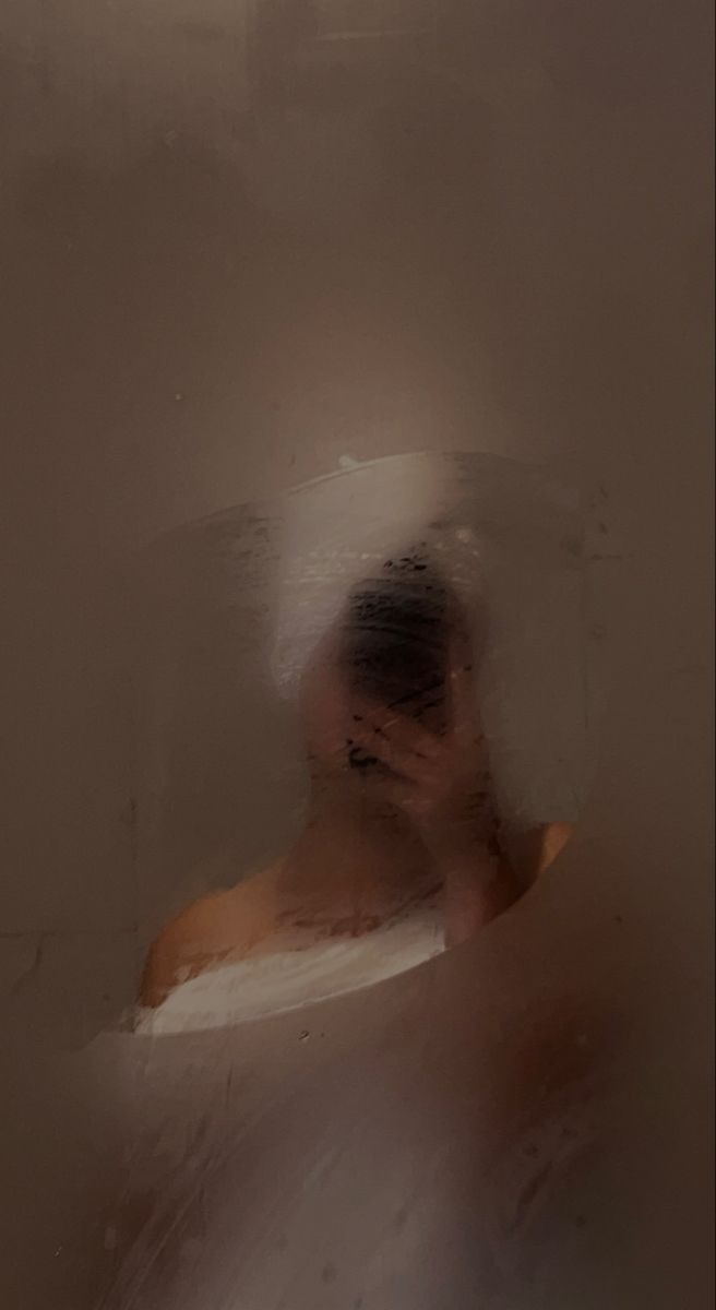 a woman in a white bath tub with her face obscured by the shower curtain