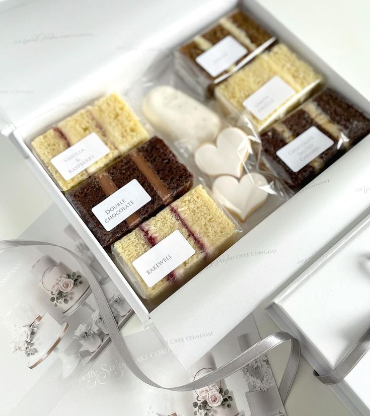 a box filled with lots of different types of cakes on top of a white table