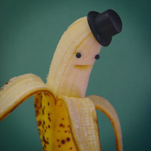 a banana with a black hat on it's head sitting in front of a green background