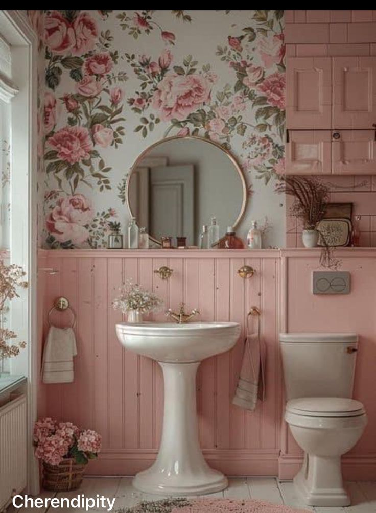 pink bathroom with floral wallpaper and white pedestal sink, toilet and mirror in the corner