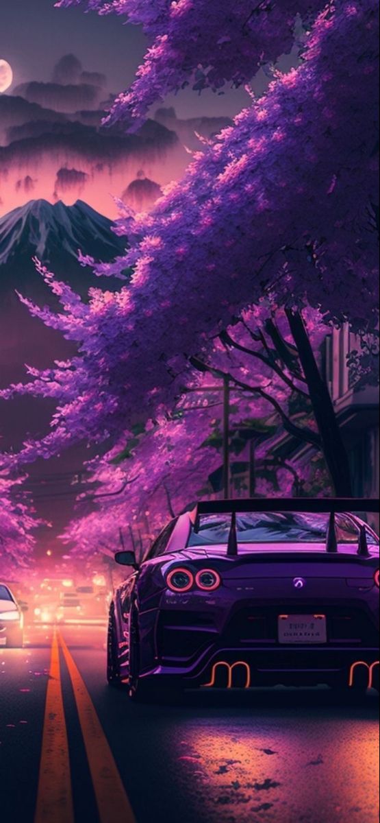 two cars are driving down the road in front of trees with purple flowers on them