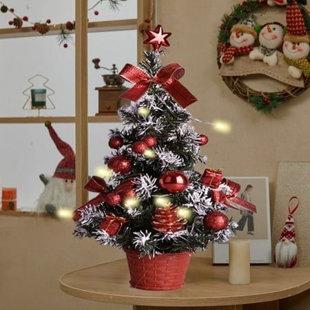 a small christmas tree with red and silver ornaments in a pot on a table next to a candle