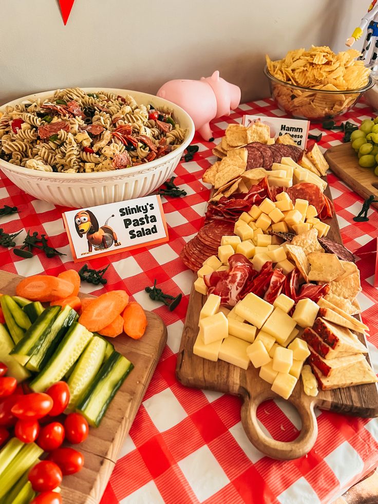 a table topped with lots of different types of cheeses and crackers next to bowls of vegetables