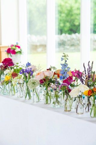 there are many vases with flowers in them on the table next to each other