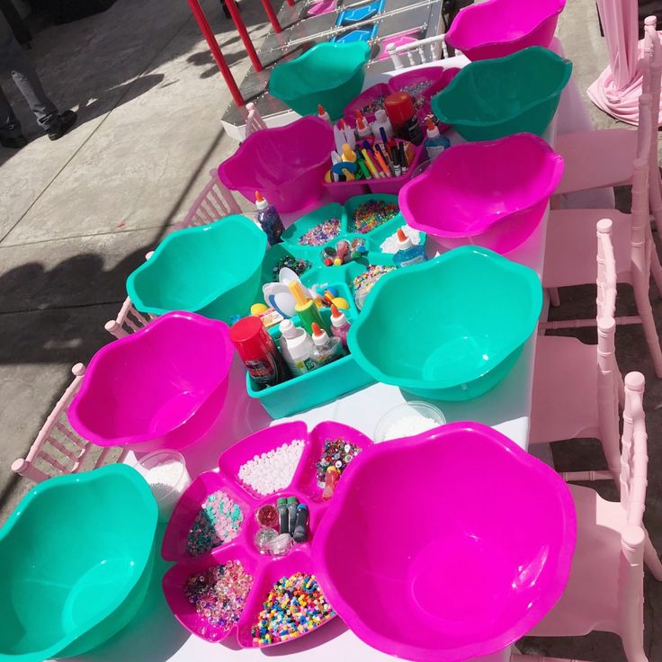 pink and blue bowls are lined up on a table with other plastic dishes in them