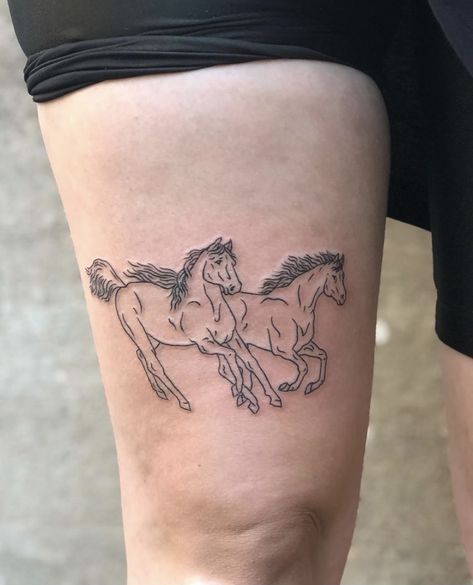 a woman's leg with a tattoo of two horses on the side of her thigh