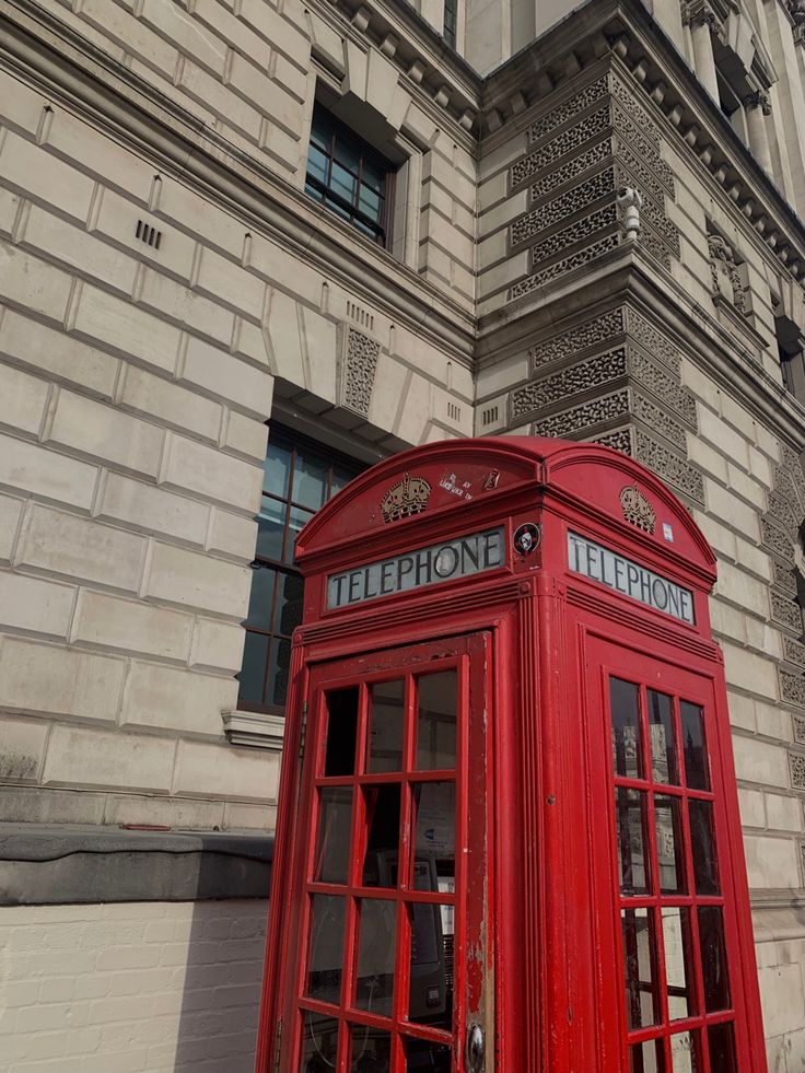 a red phone booth sitting in front of a tall building