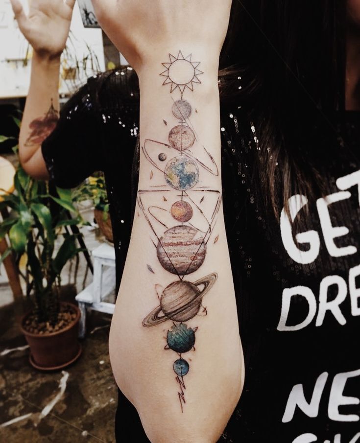 a woman is holding her hand up to her face while wearing a solar system tattoo