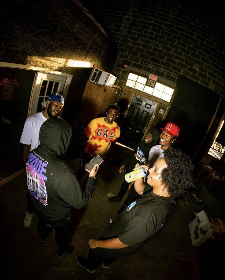 several people standing around talking to each other in a dark room with brick walls and doorways