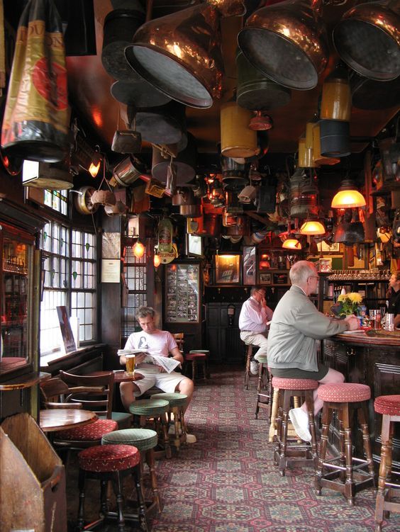 people sitting at tables in a restaurant with pots hanging from the ceiling