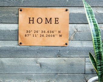 a sign on the side of a building that says home and is next to a potted plant