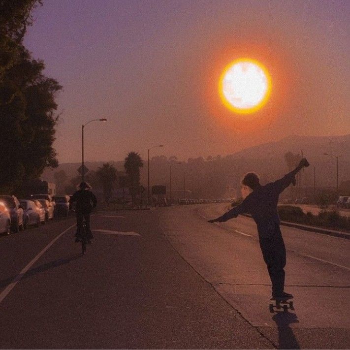 a man riding a skateboard down the side of a road under a bright sun