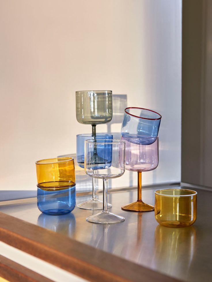 several different colored wine glasses sitting on top of a counter