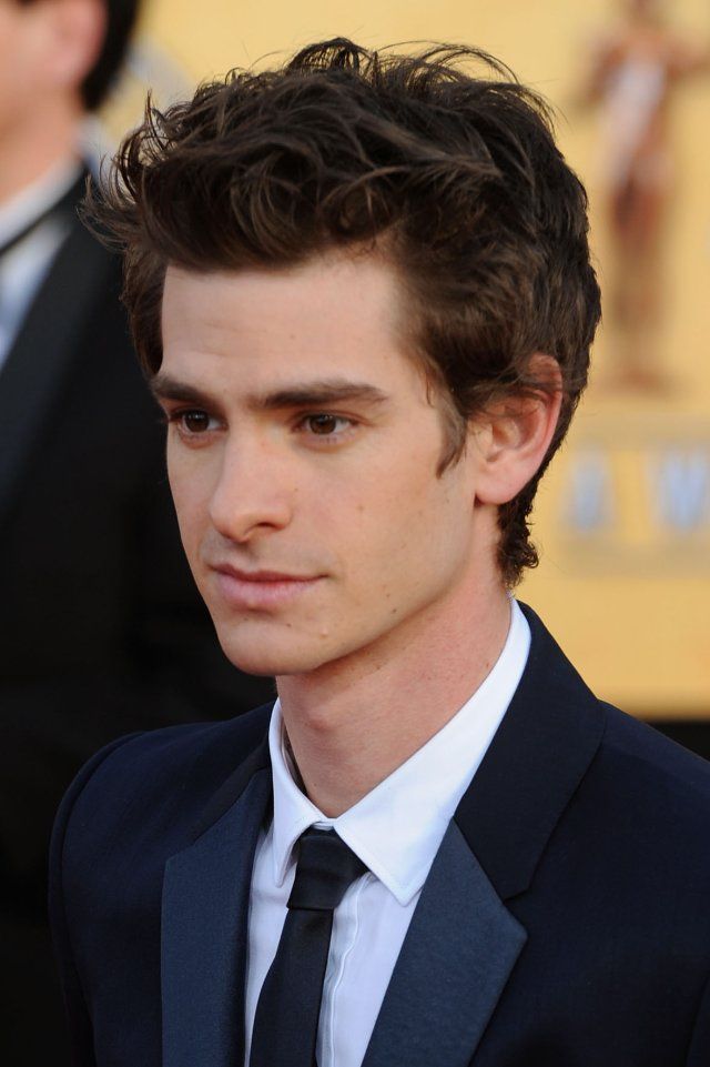 a young man in a suit and tie at an awards ceremony with other people behind him