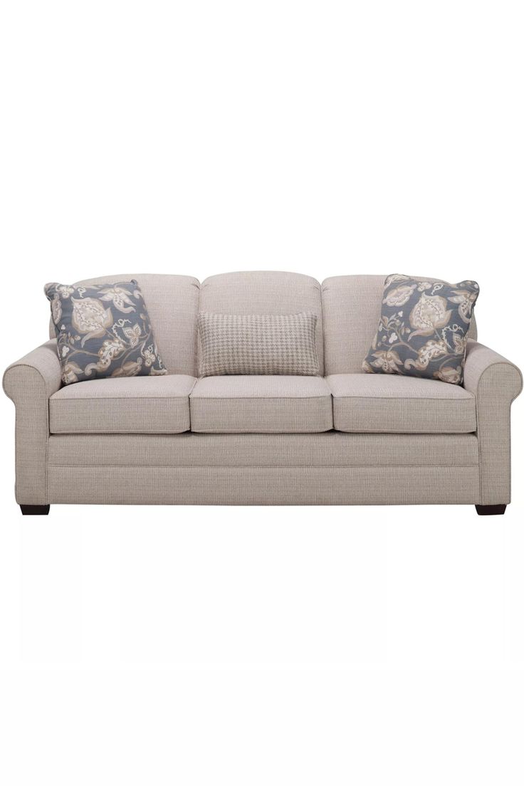 a beige couch with pillows on it and two blue throw pillows in front of it