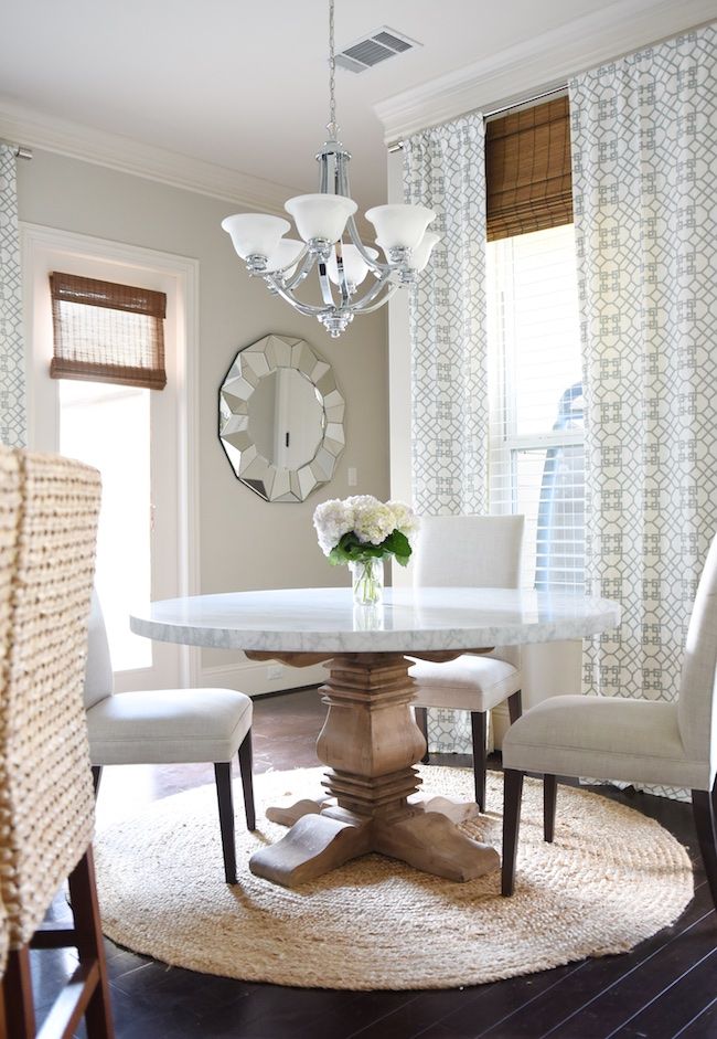 a dining room table with white chairs and a chandelier hanging from the ceiling