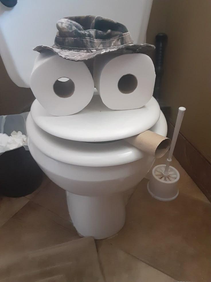 a toilet with two rolls of toilet paper on it's back and one roll sticking out of its mouth