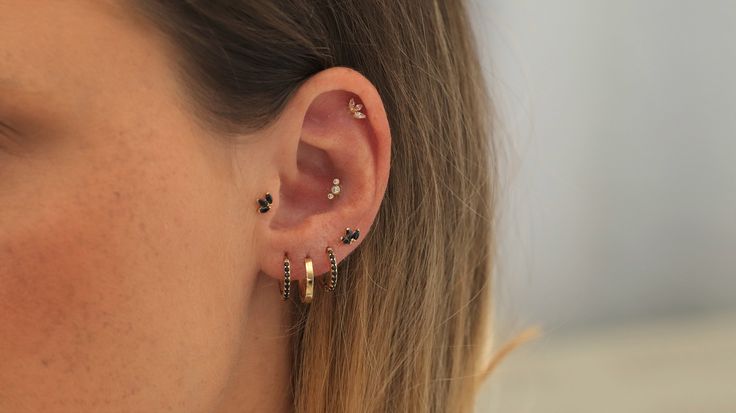 a close up of a person with ear piercings on their ears and wearing earrings