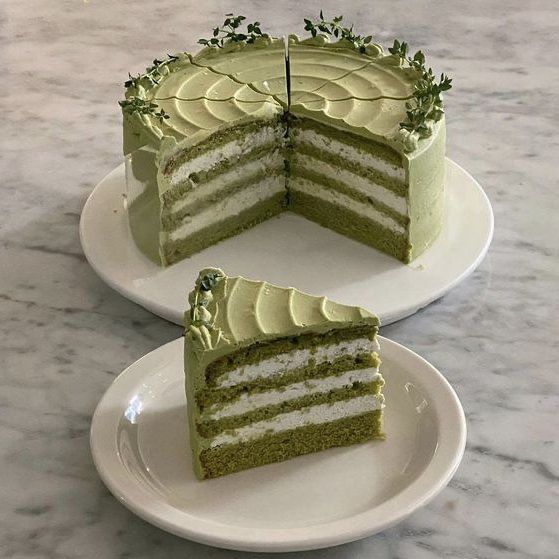 two slices of green cake sitting on top of white plates with one slice cut out