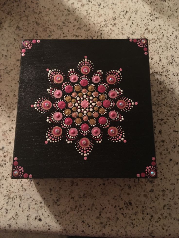 a black box with pink and brown designs on it sitting on a counter top next to a tile floor