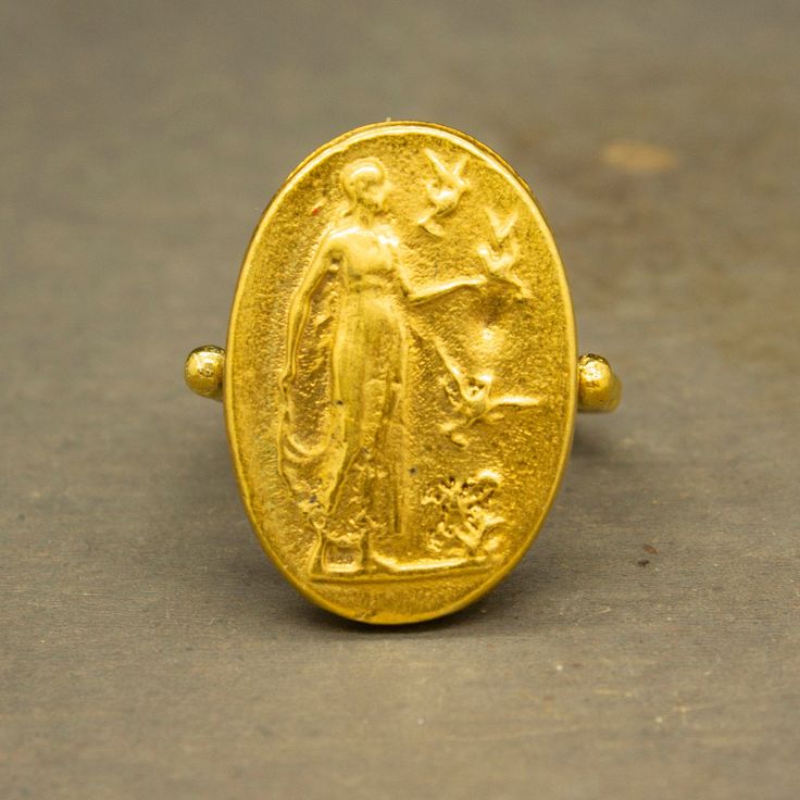 Ancient Greek Art Signed Coin Ring made 24k gold plated 925 sterling silver and used Reproduction Bronze Coin. Our shop offer free ring sizing Handcrafted hammered full round ring band size measures 2mm in width and 24k gold plated bronze coin 23x16 mm. Metal : 925 Sterling Silver Band Width : 2 mm Coin : Reproduction Bronze Coin Coin Size : 23x16 mm Ring Weight : 7.85 grams Ring Size : US 6 (The size you want is made for free). (We used the US standard sizing) **Custom Orders is Made** As pella Gold Oval Engraved Brass Ring, Antique Gold Signet Ring For Commemoration, Gold Antique Signet Ring For Commemoration, Heirloom Gold Engraved Ring For Commemoration, Gold Hallmarked Signet Ring For Commemoration, Gold Byzantine Style Ceremonial Signet Ring, Gold Byzantine Signet Ring For Ceremonial Occasions, Gold Byzantine Signet Ring For Ceremonies, Gold Byzantine Oval Ring