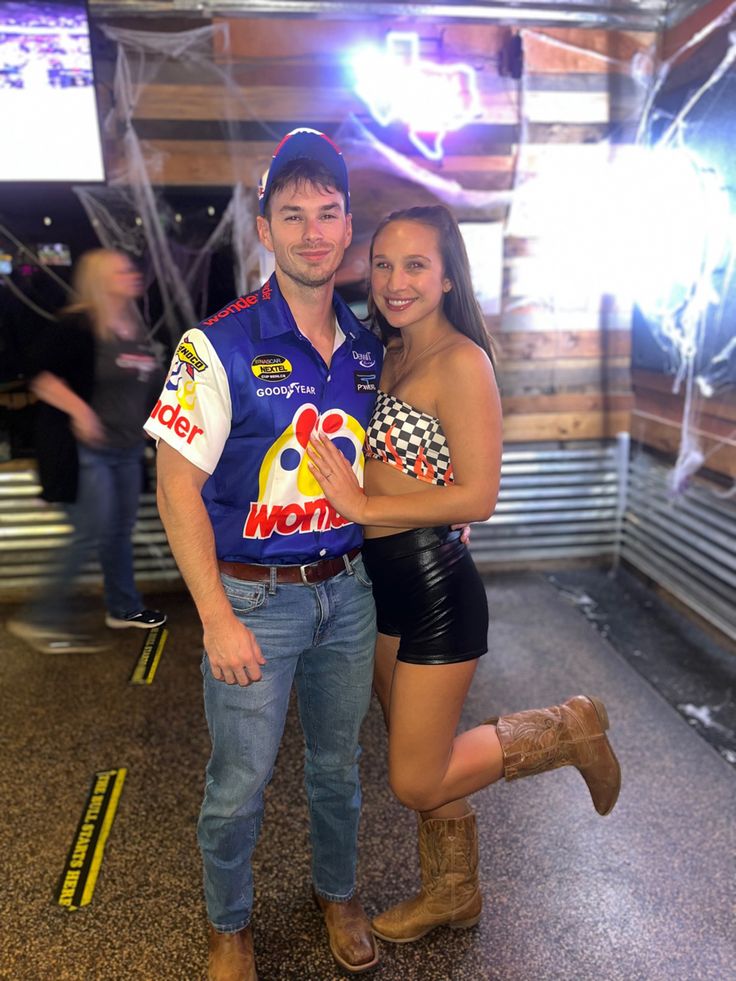 a man and woman posing for a photo in front of a stage with lights behind them