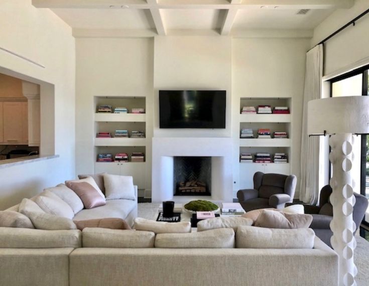 a living room filled with furniture and a flat screen tv mounted on the wall above a fire place