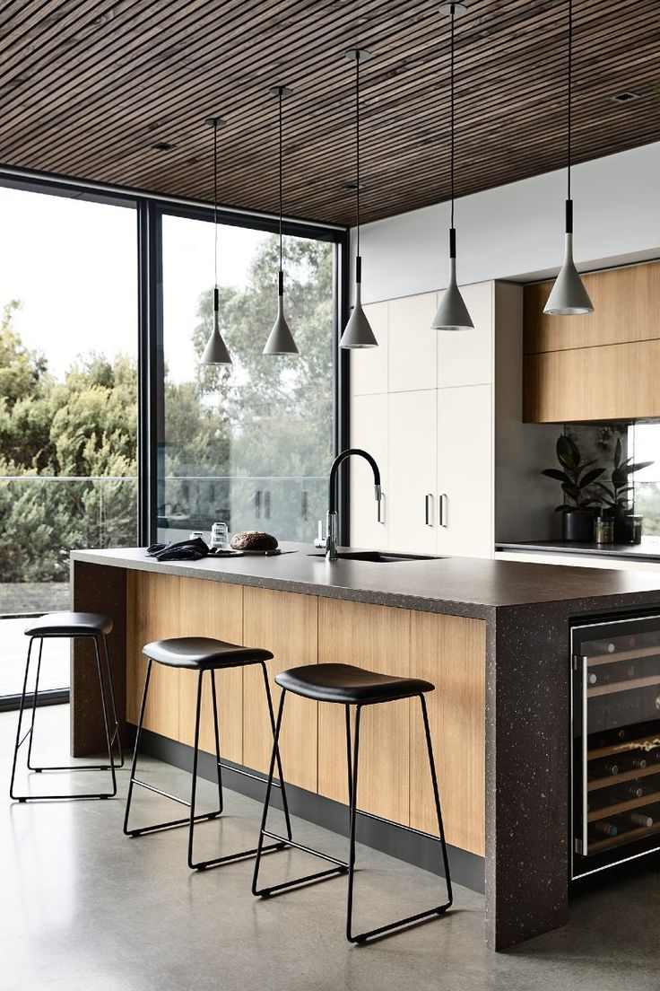 a kitchen with two stools in front of the counter and an open wine cooler