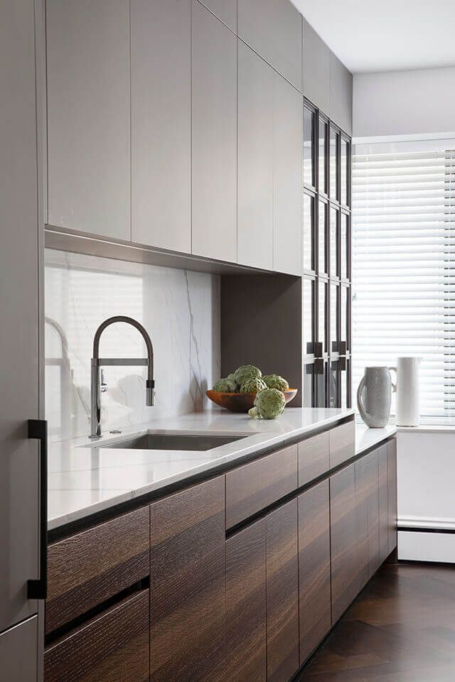 a kitchen with wooden cabinets and white counter tops, along with a bowl of vegetables