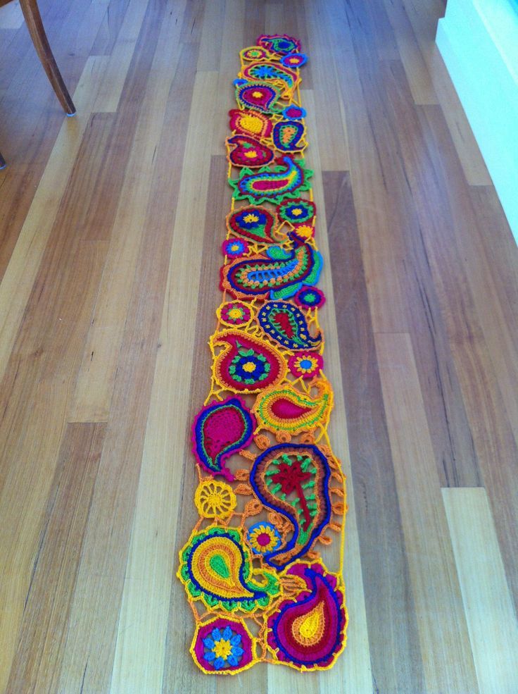 a long crocheted table runner is on the floor