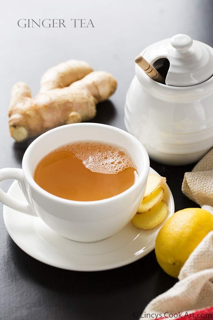 a cup of tea next to some sliced lemons and ginger