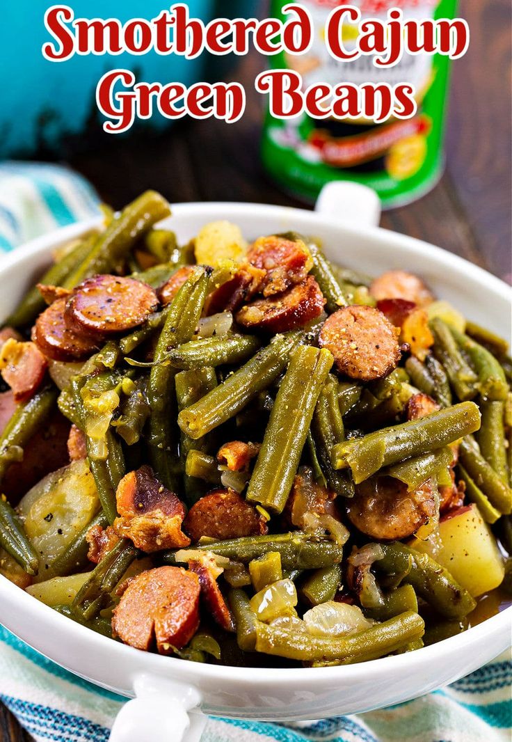 a white bowl filled with green beans and sausage on top of a blue striped towel