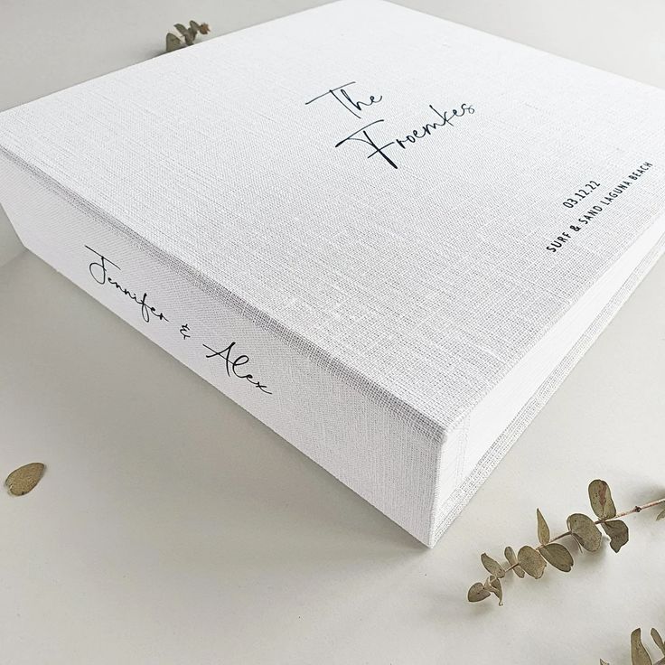 a white box with writing on it sitting next to some dried flowers and leaves in the foreground