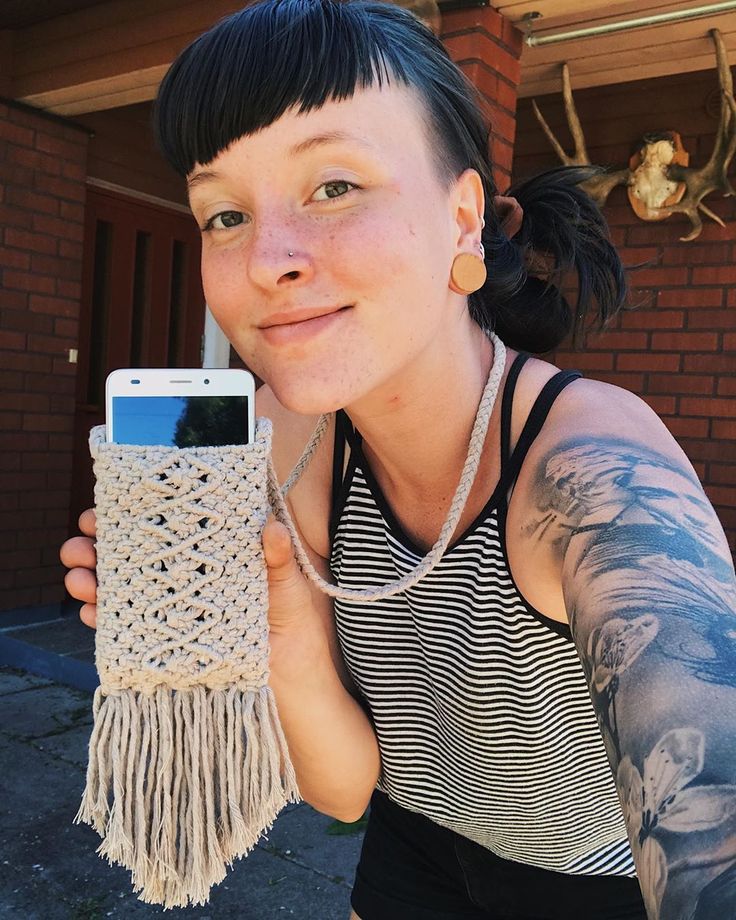 a woman holding up a cell phone in front of her face with tattoos on it