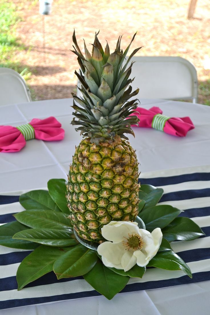 a pineapple sitting on top of a table next to a white flower and green leaves