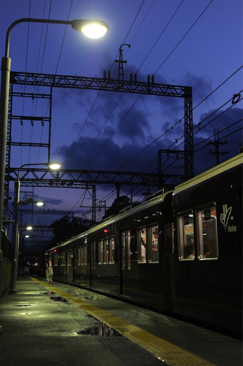 a train that is sitting on the tracks near a street light and some lights at night